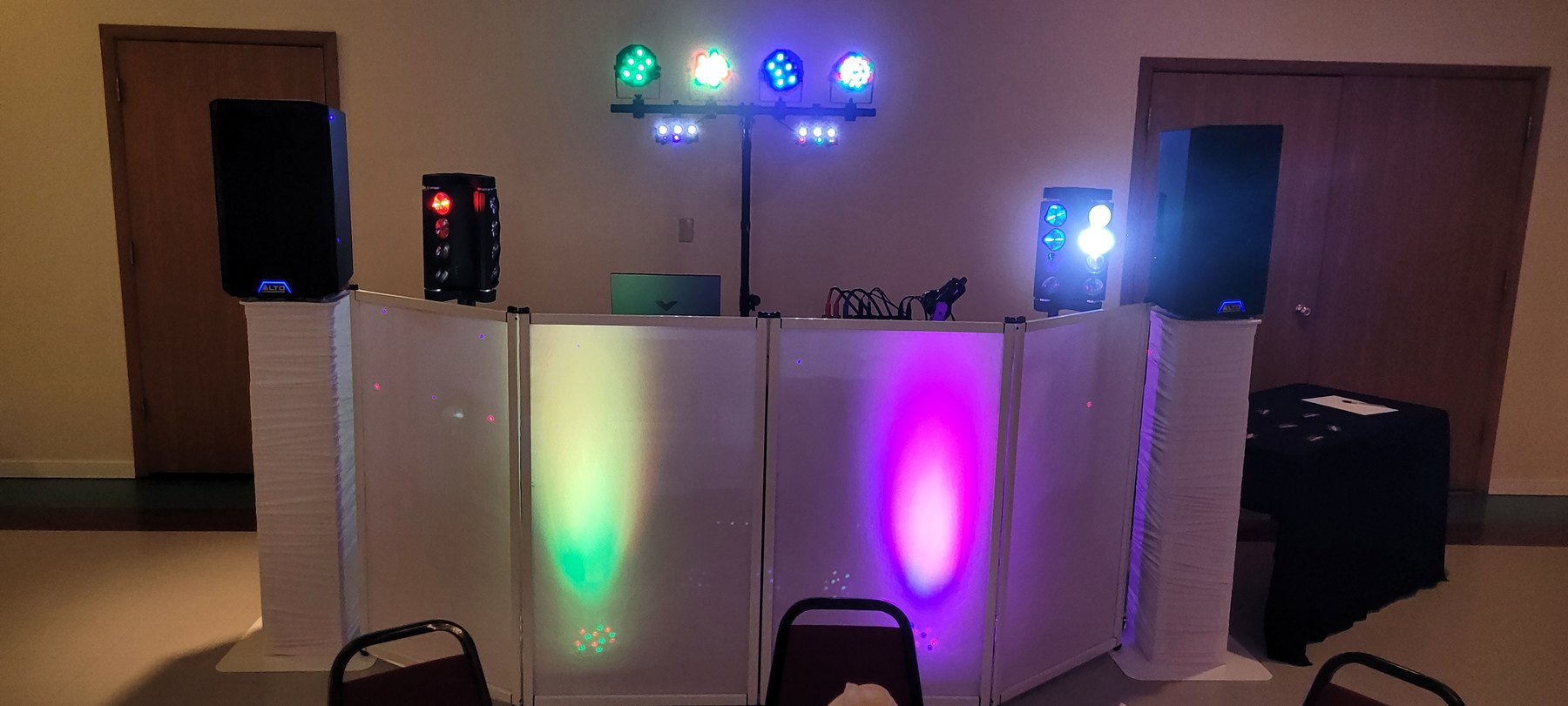 Genesis's DJ booth with speakers and colored stage lighting set up for an event