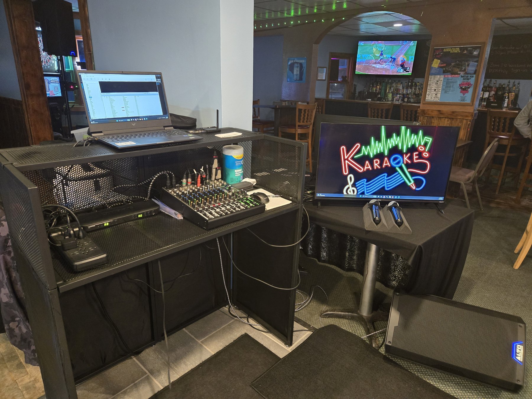 Full karaoke rig with laptop, mixer, wireless microphones and karaoke screen set up in a venue